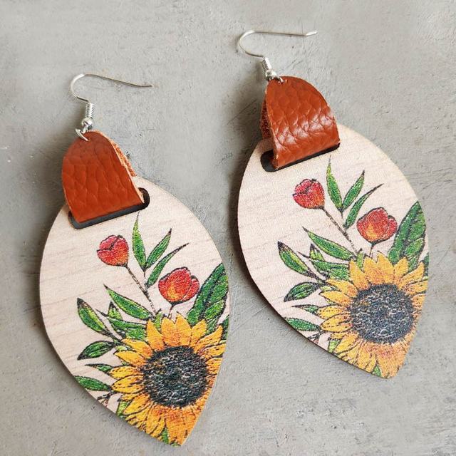 Handcrafted sunflower earrings combining warm wood tones with supple leather accents
