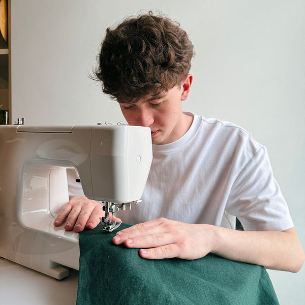 Person using a sewing machine on a white background